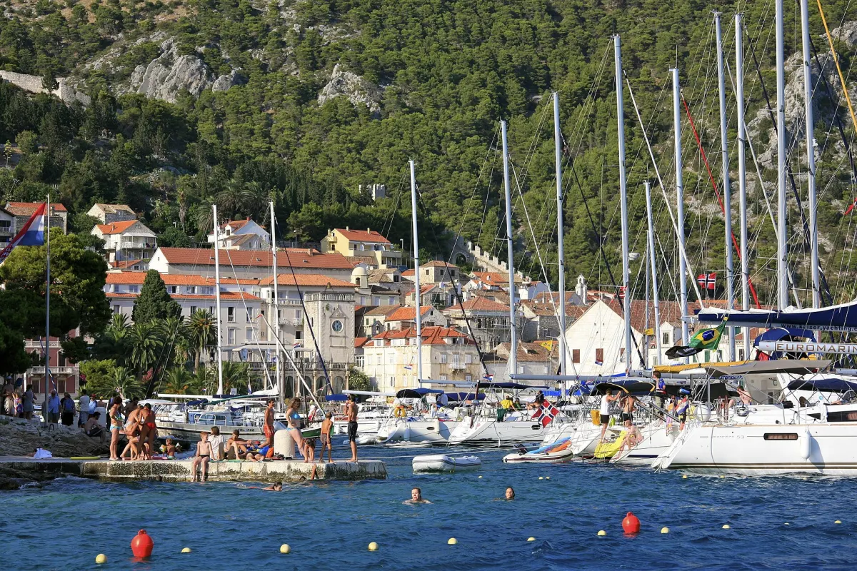Jachty przy nabrzeżu w mieście Hvar, w tle kamienne domy na zboczu