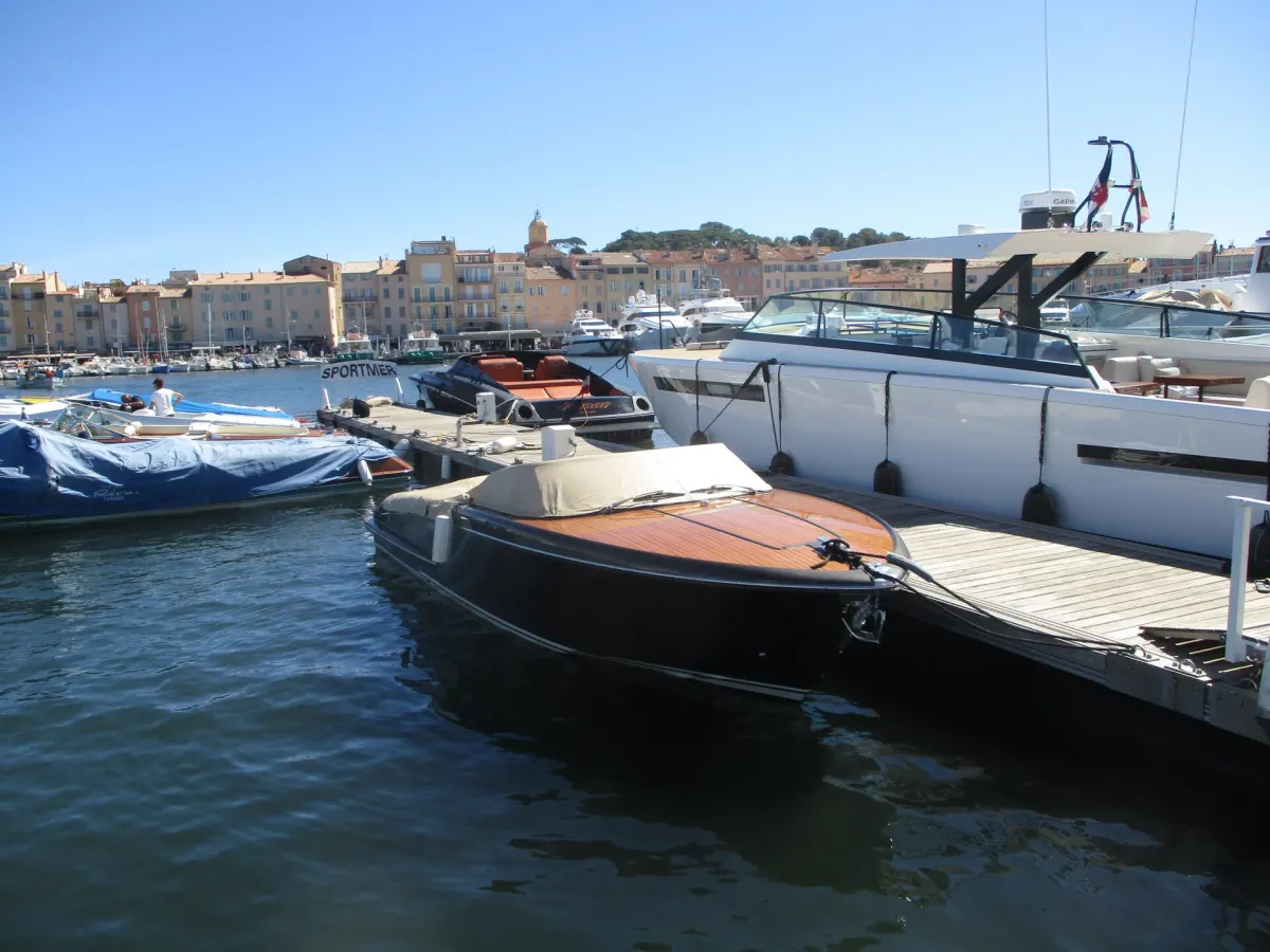 Port w Saint-Tropez: łodzie przy pomostach, w tle pastelowe kamienice i wieża kościoła