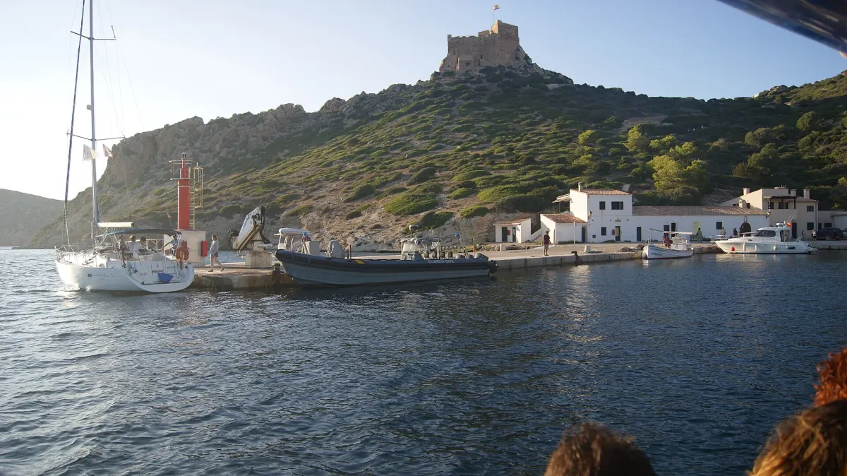 Port na wyspie Cabrera z zamkiem na wzgórzu i jachtem przy pomoście