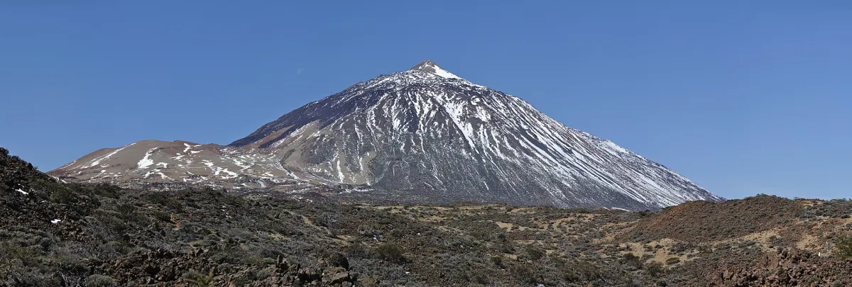 Ośnieżony stożek wulkanu Teide nad polami zastygłej lawy